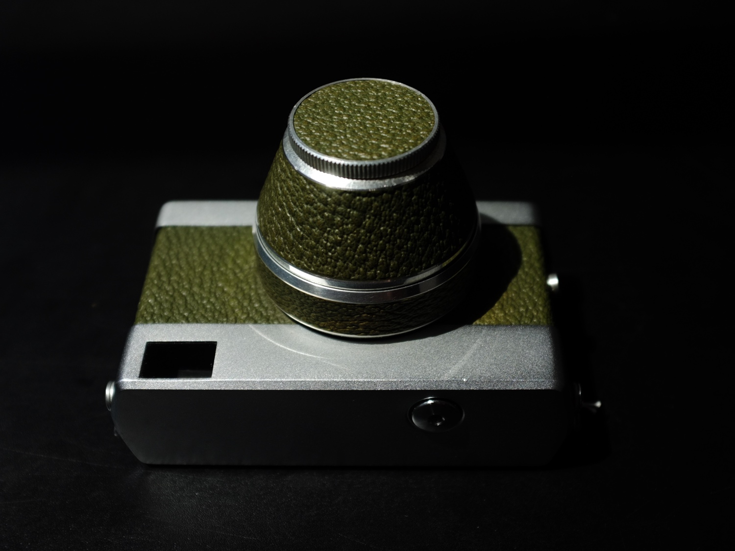 A simple rangefinder camera with olive-green leatherette surfaces and matte metal trim