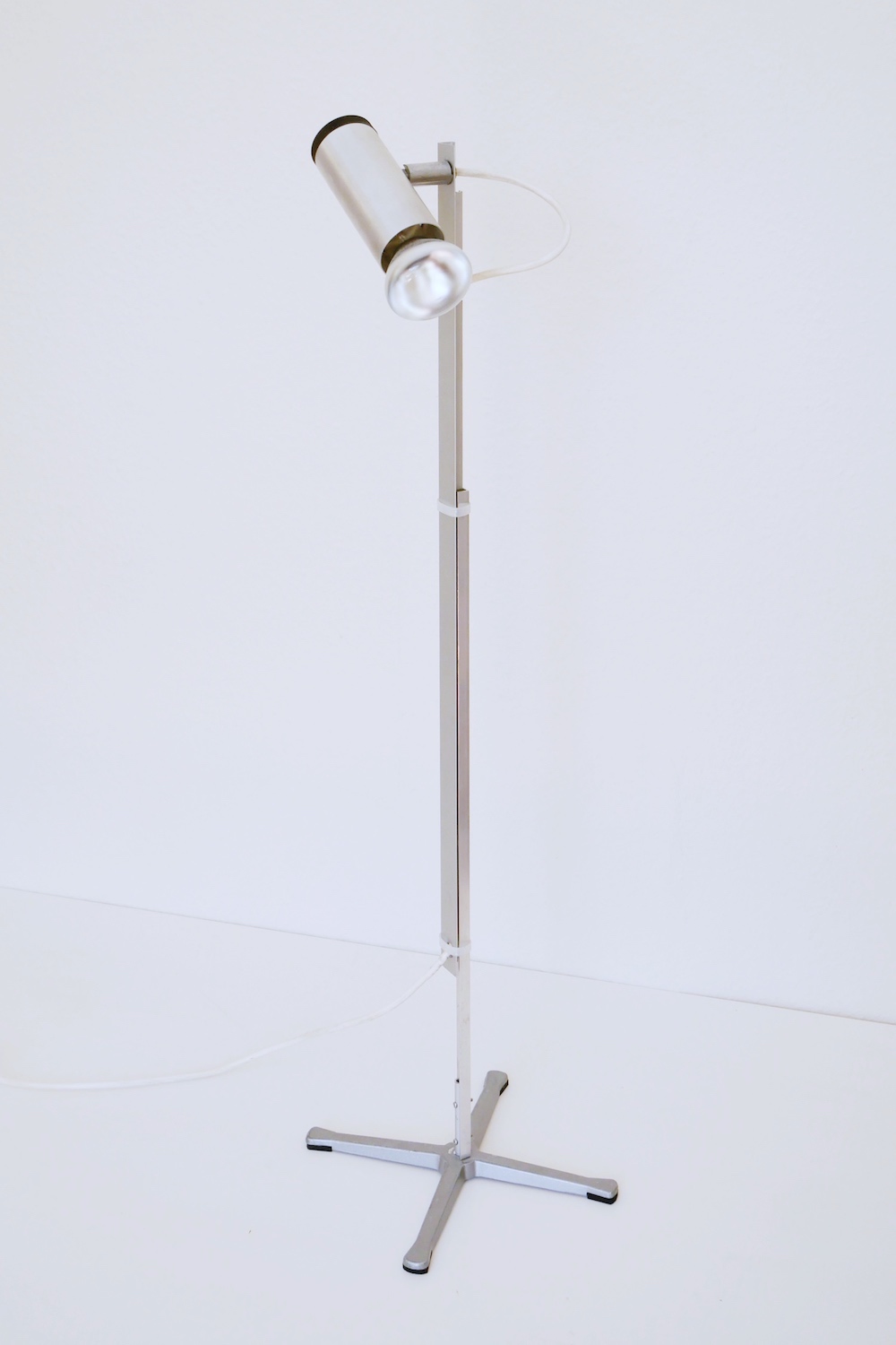 A spotlight on an aluminum bar, mounted on a cruciform metal stand