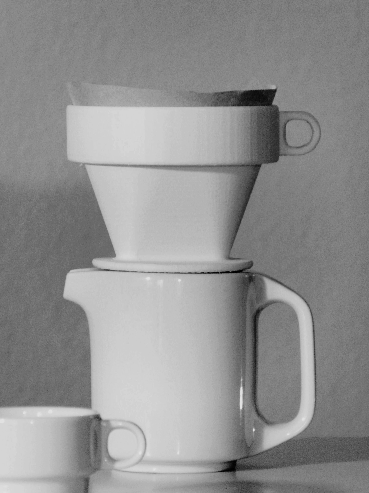 Coffee filter sitting on carafe, matching mug in foreground