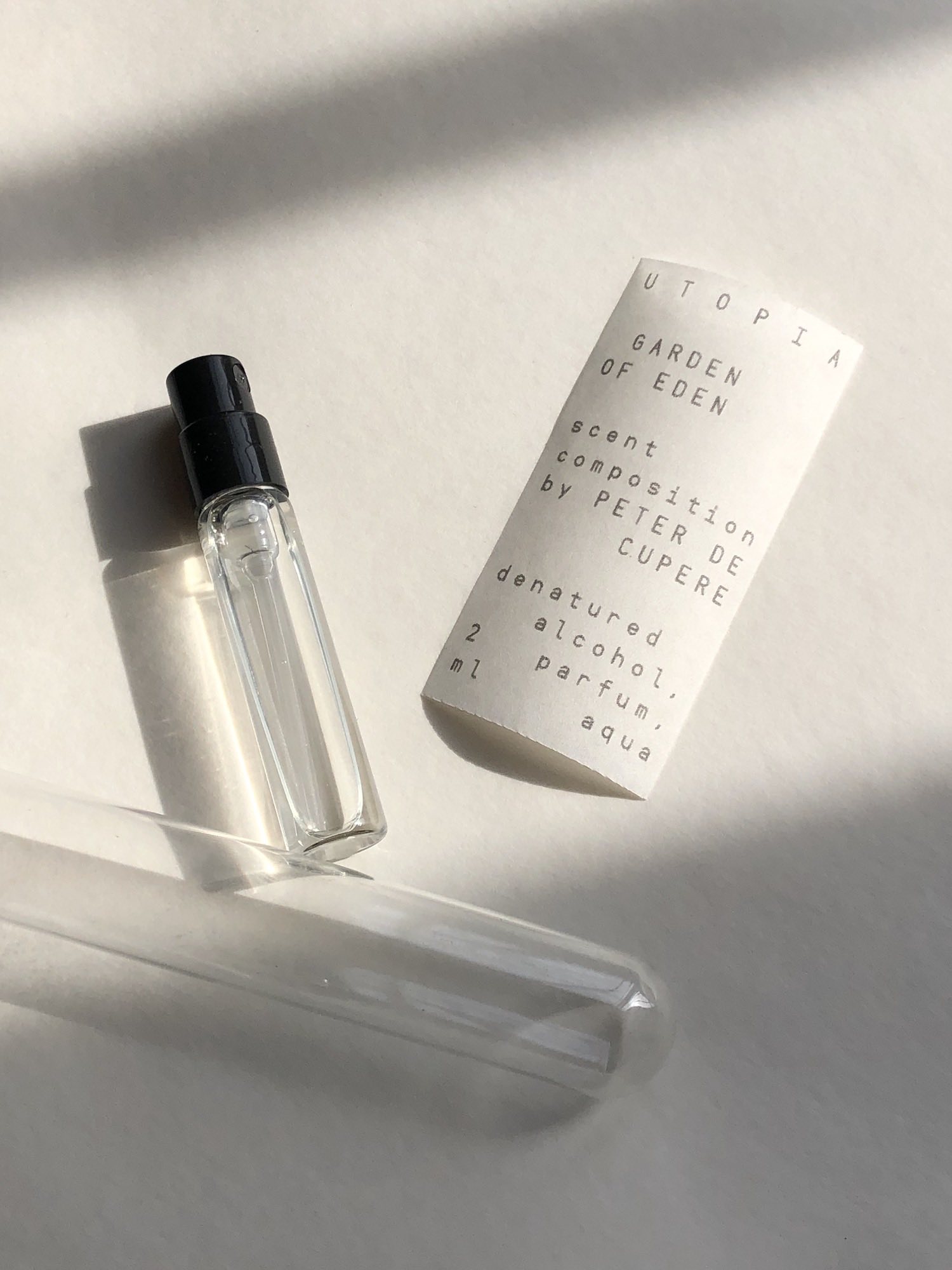 Small perfume bottle, glass tube, label laid out on table in the sun